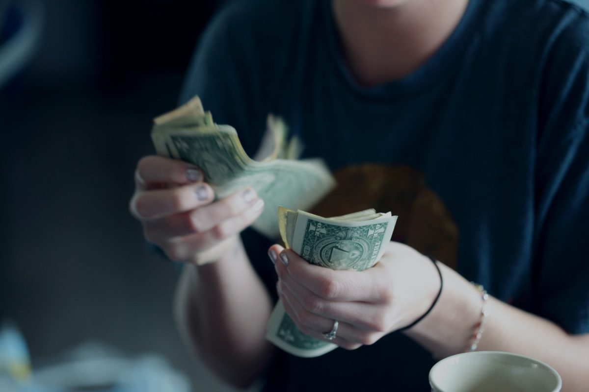 Image of woman counting $1 USD bills.